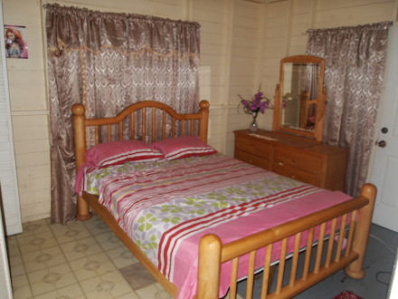 A bed room with a wooden frame and pink sheets