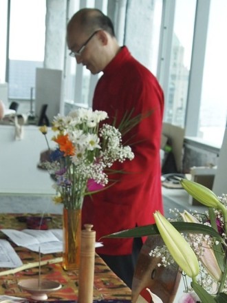 A man in red jacket standing next to flowers.
