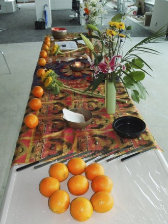 A long table with oranges and flowers on it.