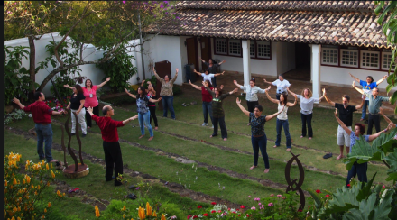 A group of people standing in the grass with their arms outstretched.